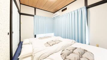 Un dormitorio con cama, ventana con cortinas, lámpara de techo y unidad de aire acondicionado.