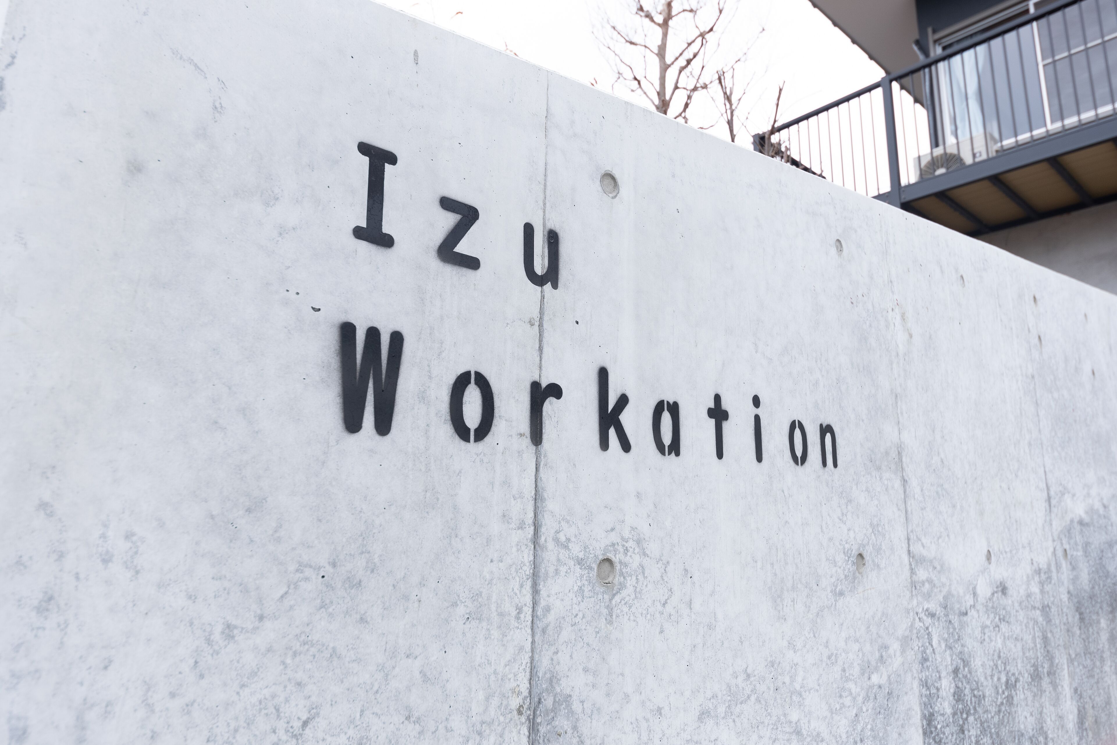A concrete wall with the text "Izu Workation" engraved on it.