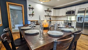 Un comedor con una mesa de madera dispuesta para cuatro personas, rodeado de sillas.