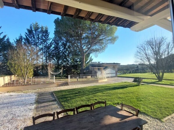 A patio with a table and chairs, a fenced garden, and a building with a staircase.