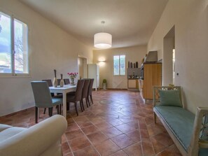 A spacious living area with a dining table, chairs, a sofa, and a kitchen in the background.