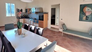 Una cocina moderna con armarios de madera, horno empotrado y comedor con mesa y sillas blancas.