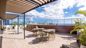 Una terrazza sul tetto con posti a sedere all'aperto, vista sull'oceano e una pergola in legno.