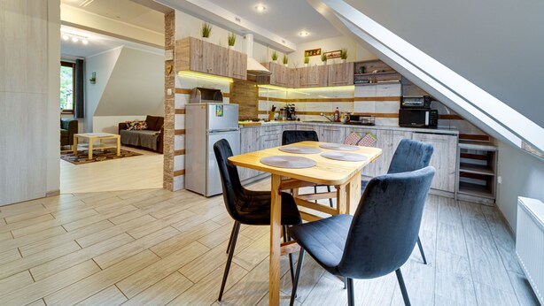 A modern kitchen with a dining area, wooden flooring, and a loft bedroom with a skylight. - Karpacz Boczna (poddasze) by Interhome (Karpacz)