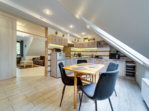 Une cuisine moderne avec un coin repas, un plancher en bois et une chambre à l’étage avec une lucarne.