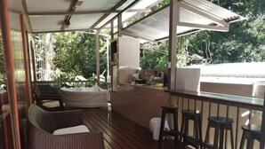 A covered outdoor area with a wooden deck, a hot tub, and a bar area with stools. - HOTEL VILLAS MYA Puerto Viejo Limon CR (Cahuita)