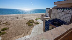 Vista da praia com uma estrutura em azulejos e uma piscina pequena.