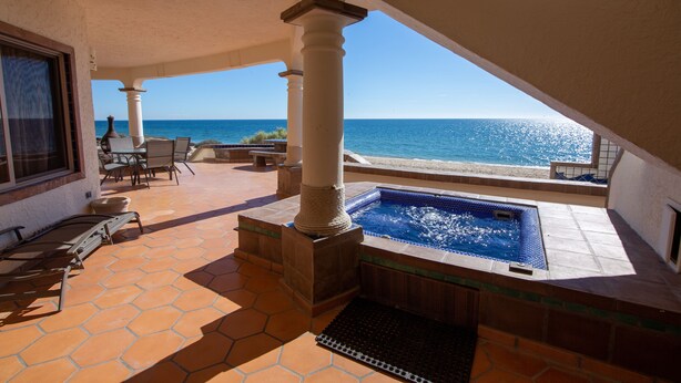 Área da piscina com vista para o oceano, mobiliário de exterior e uma banheira de hidromassagem.