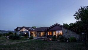A two-story house with a stone facade, large windows, and a patio area. - Kingsley Lake View & Paddocks - A group retreat with hot tubs, sports bars & spectacular lake views (Chew Stoke)