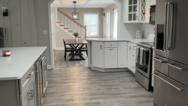 Een moderne keuken met witte kasten, roestvrijstalen apparatuur en een houten vloer.