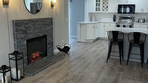 Een moderne keuken met witte kastjes, een ingebouwde magnetron en een stenen open haard.