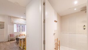 A modern bathroom with a walk-in shower, a toilet, and a sink. There is a window with a view of the outside. - Plaza del Pan Deluxe 1 (Sevilla)