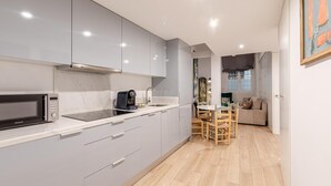 A modern kitchen with grey cabinets, a microwave, and a coffee machine. There is a dining area with a table and chairs. - Plaza del Pan Deluxe 2 (Sevilla)