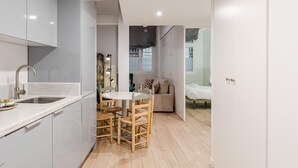 A modern kitchen with a sink, wooden chairs, and a dining table. - Plaza del Pan Deluxe 2 (Sevilla)