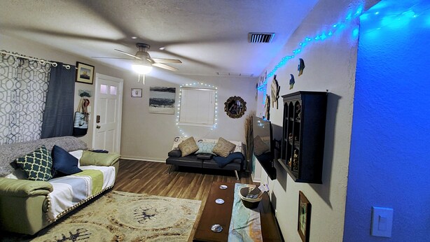 Ein Wohnzimmer mit Deckenventilator, einer Couch, einem Couchtisch und Wanddekorationen.