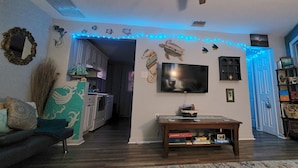 Ein Wohnzimmer mit Fernseher, Couchtisch und Bücherregal.