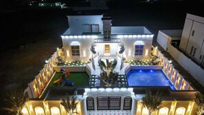A large, well-lit house with a swimming pool, a children's play area, and a car parked in front. - Discovery Guest House -Sur (Sur)