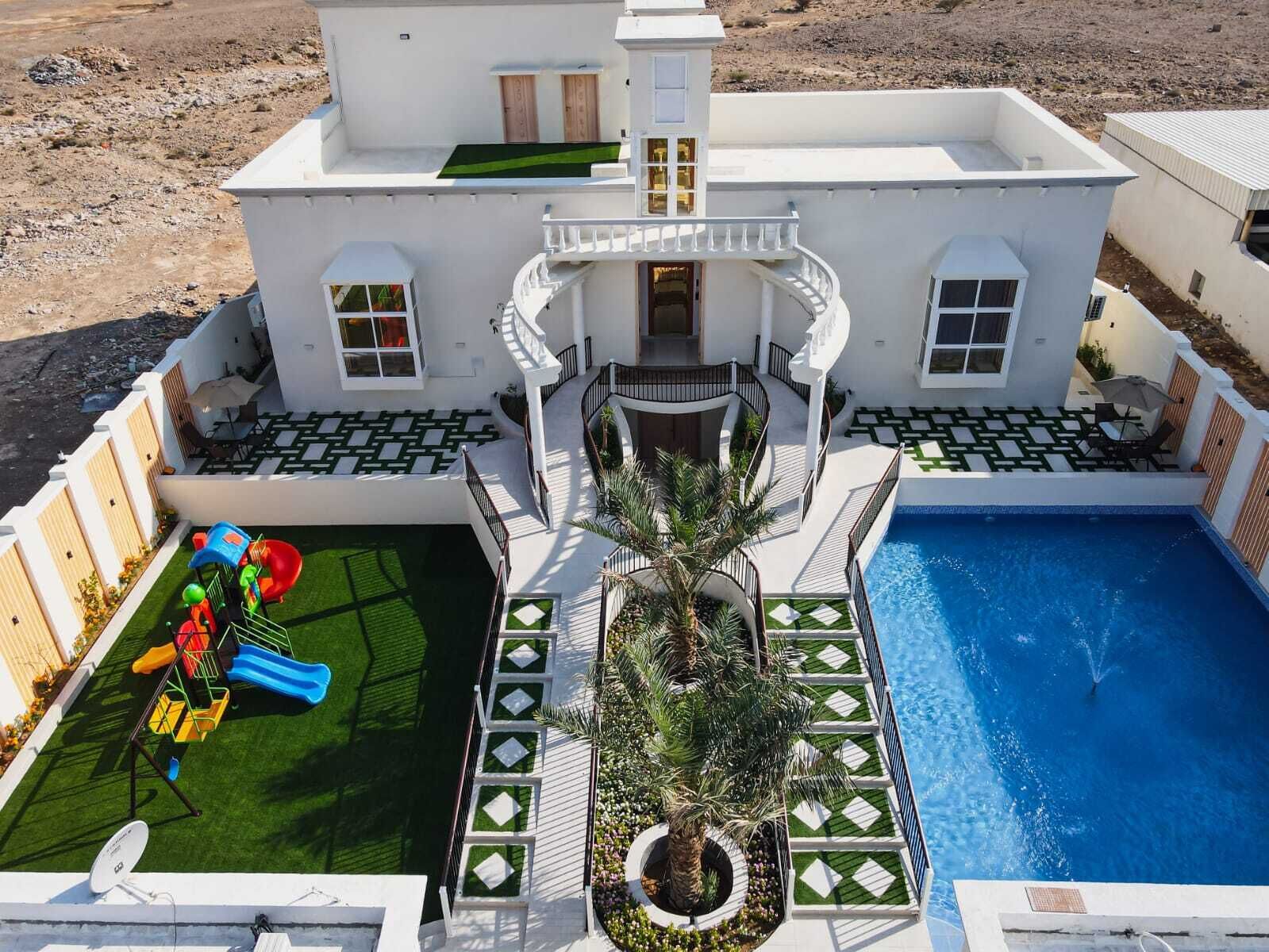 Una villa moderna con piscina, área de juegos para niños y jardín ajardinado.