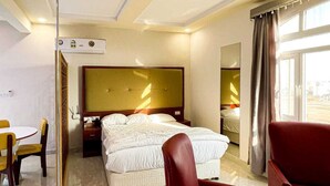 A hotel room with a large bed, a desk, and two red armchairs. - Discovery Guest House -Sur (Sur)