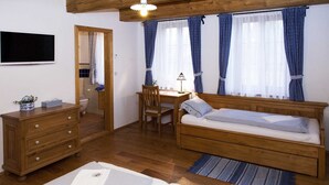 A cozy room with a wooden bed, a desk, a chair, a dresser, and a television. - Newly built cottage with pool and  large fenced garden (Ždár nad Sázavou)