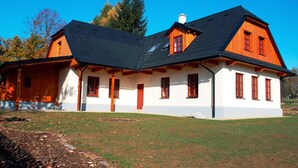 A two-story house with a sloped roof, wooden exterior, and red windows. - Newly built cottage with pool and  large fenced garden (Ždár nad Sázavou)