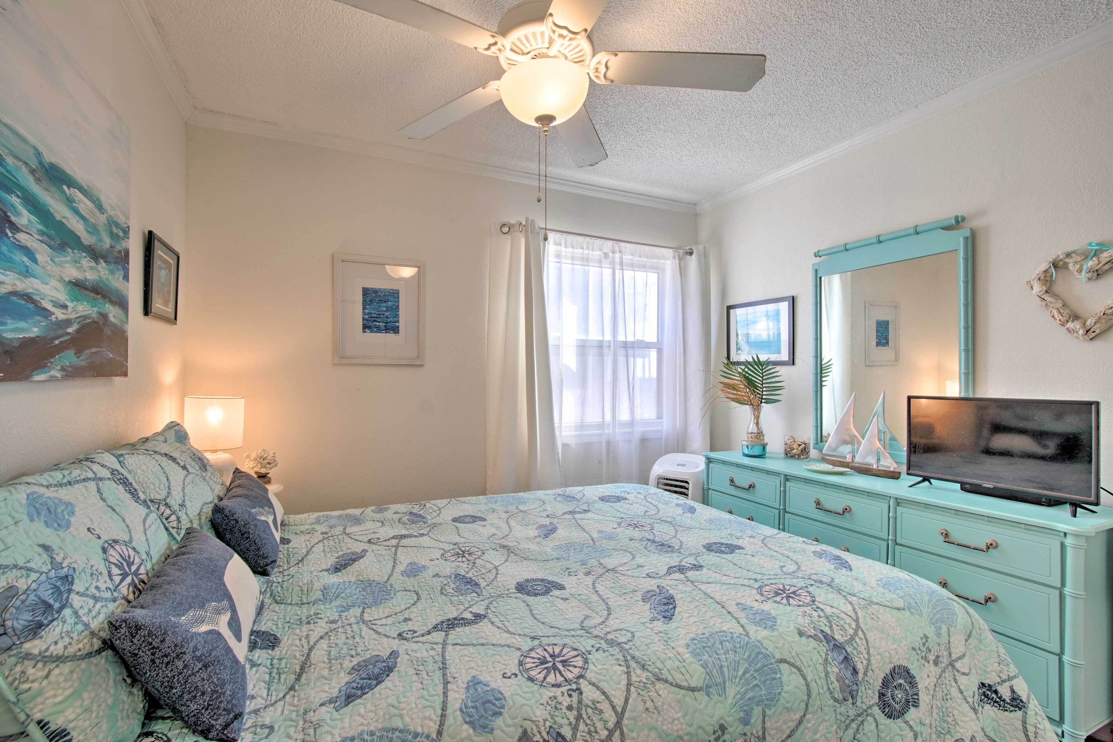 A bedroom with a bed, a ceiling fan, a television, and a dresser.
