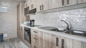 Una cocina moderna con armarios de madera, un lavamanos de acero inoxidable y un horno empotrado.