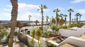 Un hotel costero con palmeras, edificios blancos y vista al mar.