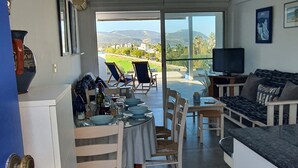 A modern kitchen with a dining area, a sofa, and a TV. - Ithaki 2 Bedroom Penthouse (Λατσί/ Πόλη Χρυσοχούς)
