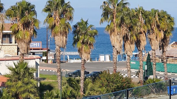 A coastal view with palm trees, a parking lot, and a sign that reads "CHI". - Ithaki 2 Bedroom Penthouse (Λατσί/ Πόλη Χρυσοχούς)