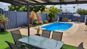 A backyard with a swimming pool, artificial grass, and a table with chairs. - Sun City Motel (Bundaberg North)