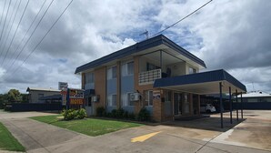 A motel with a reception area, a covered parking area, and a small lawn. - Sun City Motel (Bundaberg North)