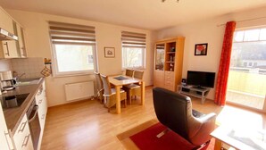 Un soggiorno luminoso con zona pranzo, cucina e televisore.