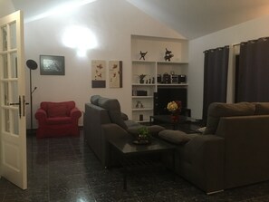 A living room with a sofa set, a red armchair, a coffee table, and a fireplace. - Chalet Casa Paula with Sea and Mountain View, Pool, Garden & Wi-Fi (Yaiza)