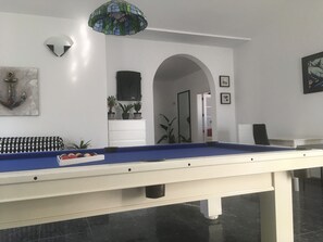 A pool table with a blue felt surface, a white cabinet with potted plants, a framed picture, and a chandelier. - Chalet Casa Paula with Sea and Mountain View, Pool, Garden & Wi-Fi (Yaiza)
