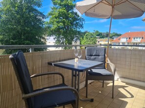 Ein Balkon mit Tisch, Stühlen und Sonnenschirm.