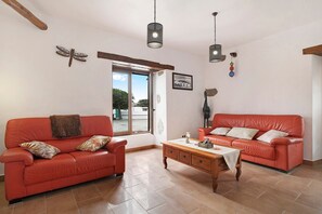 A living room with two red sofas, a wooden coffee table, and hanging lights.