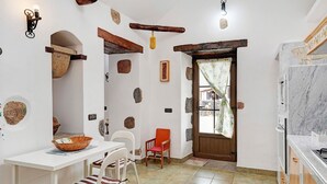 Une cuisine aux murs blancs, avec une porte en bois et un plan de travail en marbre.