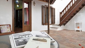 Un livre intitulé « Tesoros de la Isla » est posé sur une table, à côté d’un escalier en bois, et un mur blanc est agrémenté de volets.