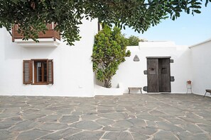 A courtyard with stone flooring, a wooden door, and a bench. - Holiday Home with Mountain Views, Balcony and Wi-Fi (Los Valles)
