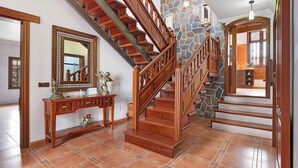 A wooden staircase with a stone wall, a console table with decorative items, and a mirror. - Holiday Home with Mountain Views, Balcony and Wi-Fi (Los Valles)