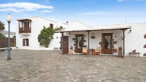 A building with a stone-paved courtyard, a balcony, and a door with a wooden frame. - Holiday Home with Mountain Views, Balcony and Wi-Fi (Los Valles)