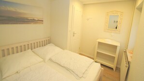 Un dormitorio con una cama, una mesita de noche, un espejo y un estante.