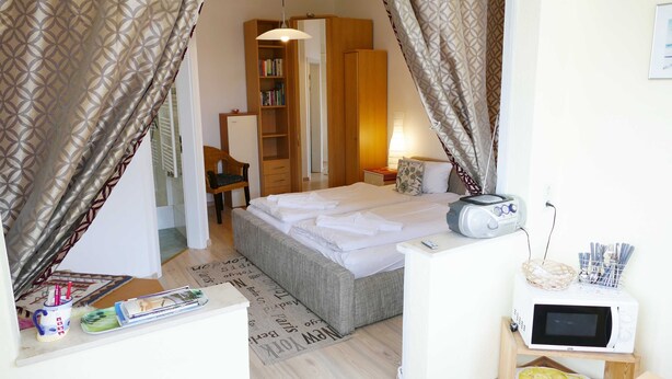 Ein gemütliches Schlafzimmer mit Bett, Nachttisch, einer Mikrowelle und einem Bücherregal.