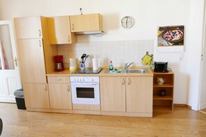 Une cuisine avec des meubles de rangement en bois, une cuisinière, un évier et une horloge au mur.