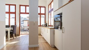 Eine moderne Küche mit Holzboden, weißen Schränken und einem Essbereich mit Tisch und Stühlen.