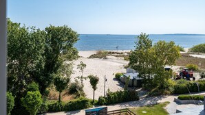 Vistes a la platja sota un cel clar, amb sorra daurada i alguns arbres.
