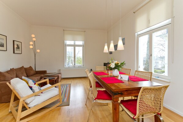 Un salon moderne avec une table à manger en bois, des chaises en osier et un canapé.