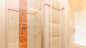 A modern bathroom with a shower, tiled walls, and a white radiator.