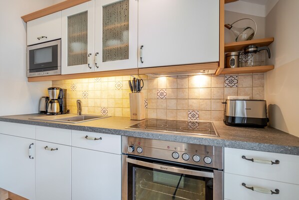 A modern kitchen with white cabinets, a built-in oven, a coffee maker, and a toaster.